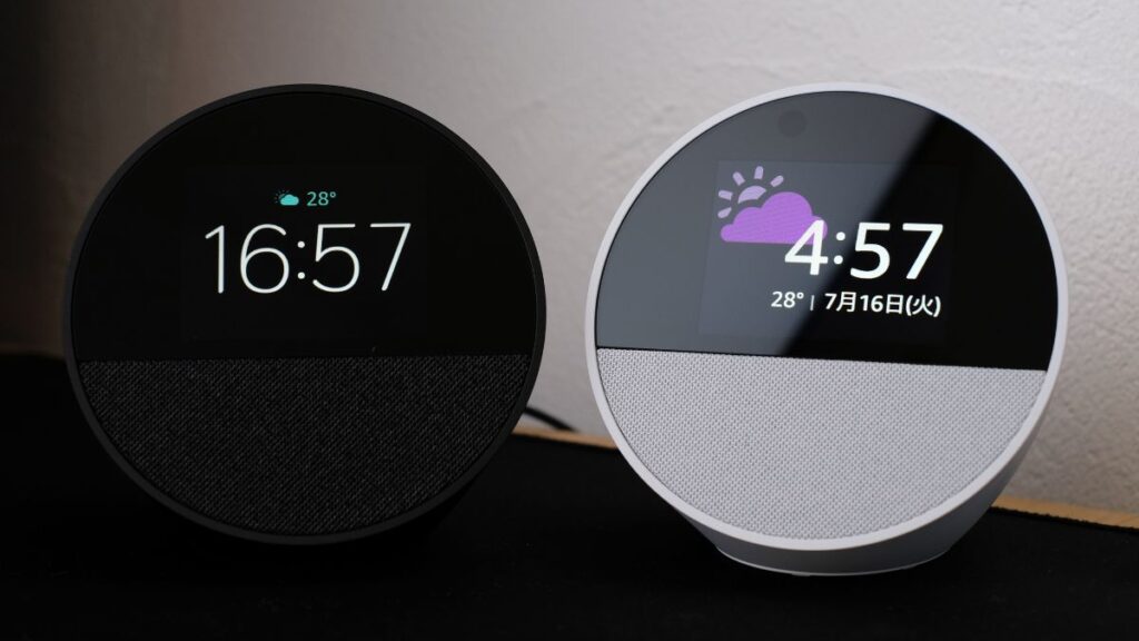 Echo Spot(ブラックとホワイト)の2台並び(それぞれ異なる文字盤デザインで時計と天気を表示)